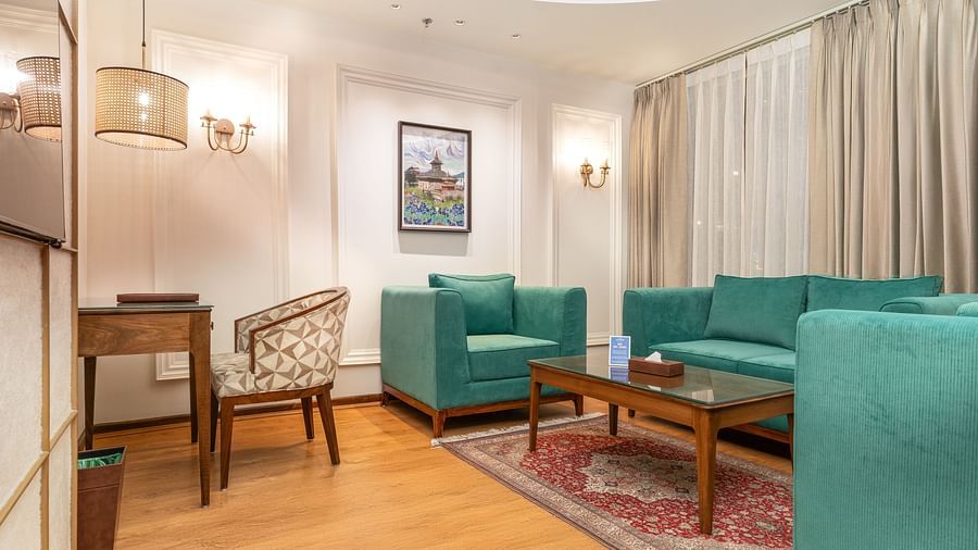An image of the lounge space with teal coloured sofas and a writing desk - Sarovar Premiere, Srinagar